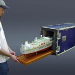 A view of the the engineering scale model of the Sea Launch Commander sliding into its custom shipping case