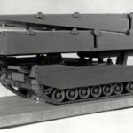 Three quarter view of an engineering scale model of a self-propelled tank-launched bridge with bridge in retracted position
