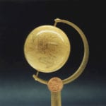 Detail view of a museum scale model of a tiny world globe created for the Rosalie Whyel Museum with a penny coin for scale